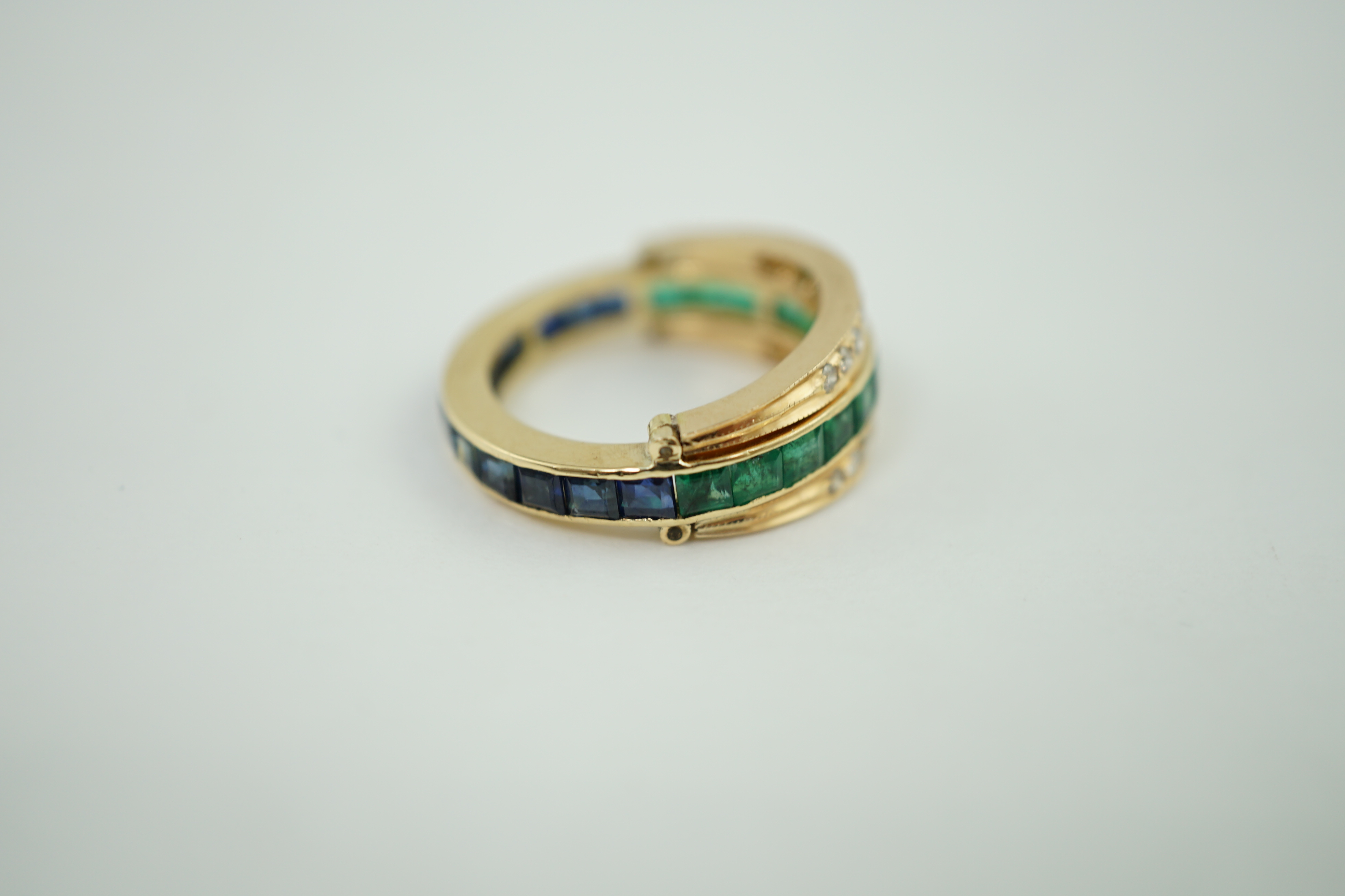 A recent gold, emerald, sapphire and diamond set triple band swivelling eternity ring